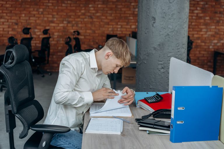 Business professional deeply focused on analyzing paperwork in a modern office setting.